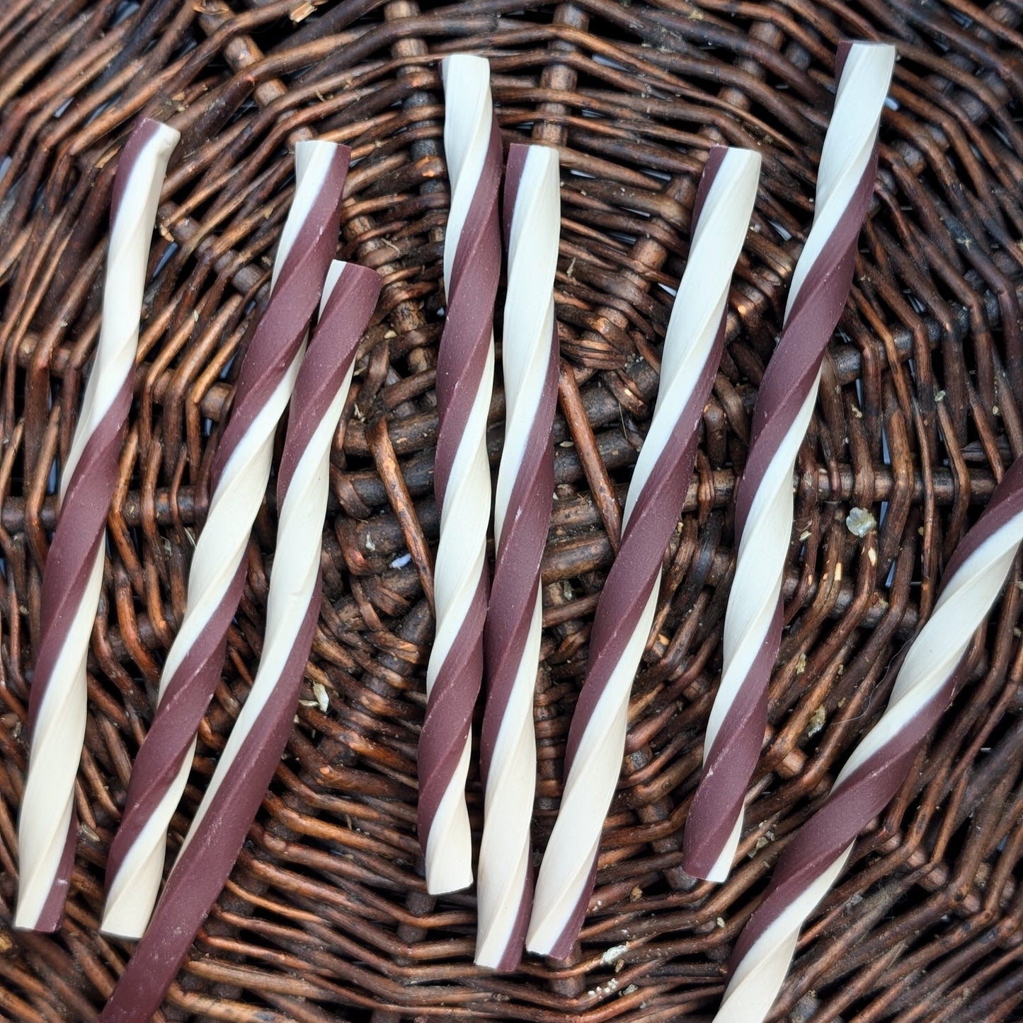 Twisted purple and white sticks on a wicker surface