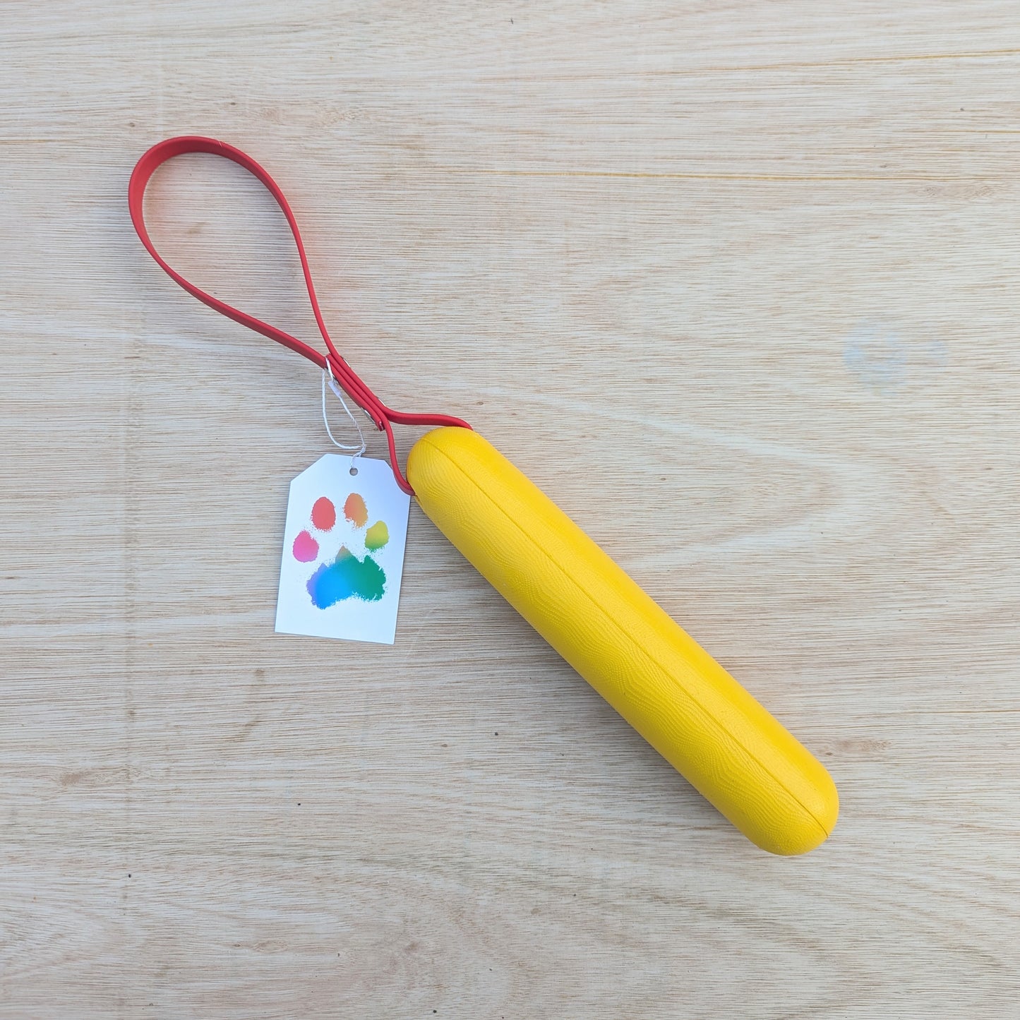 A yellow foam buoy dog tug toy with a red BioThane handle