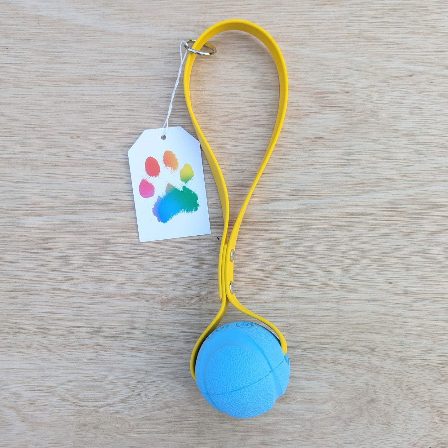 A blue dog ball with a yellow BioThane handle