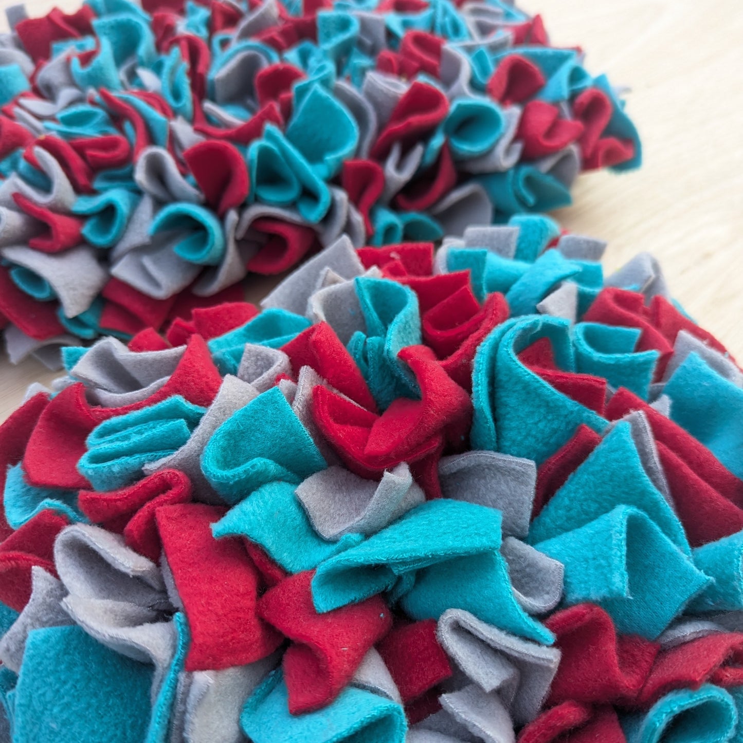 a close up of a red blue and grey fleece snuffle mat