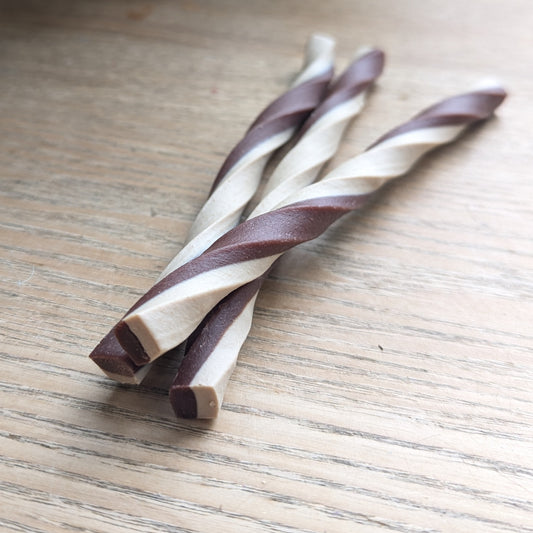 three blueberry and sweet potato veg chew twists, one is lying on top of the others. Close up of the ends of the twists