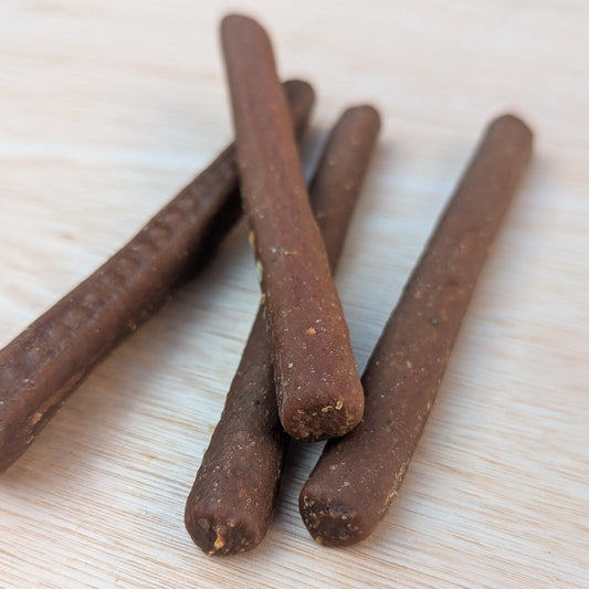 a close up of four pure turkey chew sticks. One is lying on top of the others