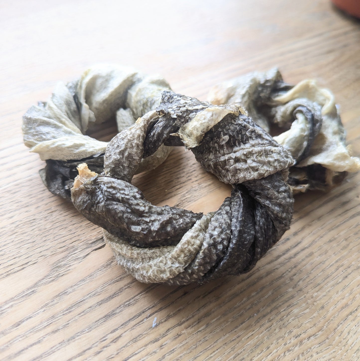 three cod skin doughnut dog chews next to each other in a triangle shape. One is propped up against the others closer to the camera