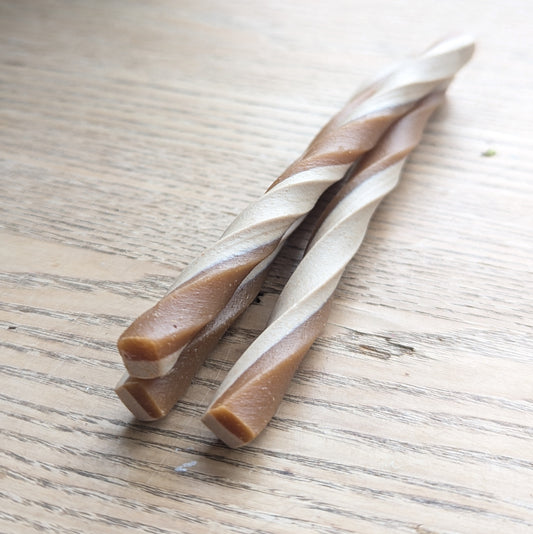 three peanut butter veg chew twists, one is lying on top of the others. Close up of the end of the twists