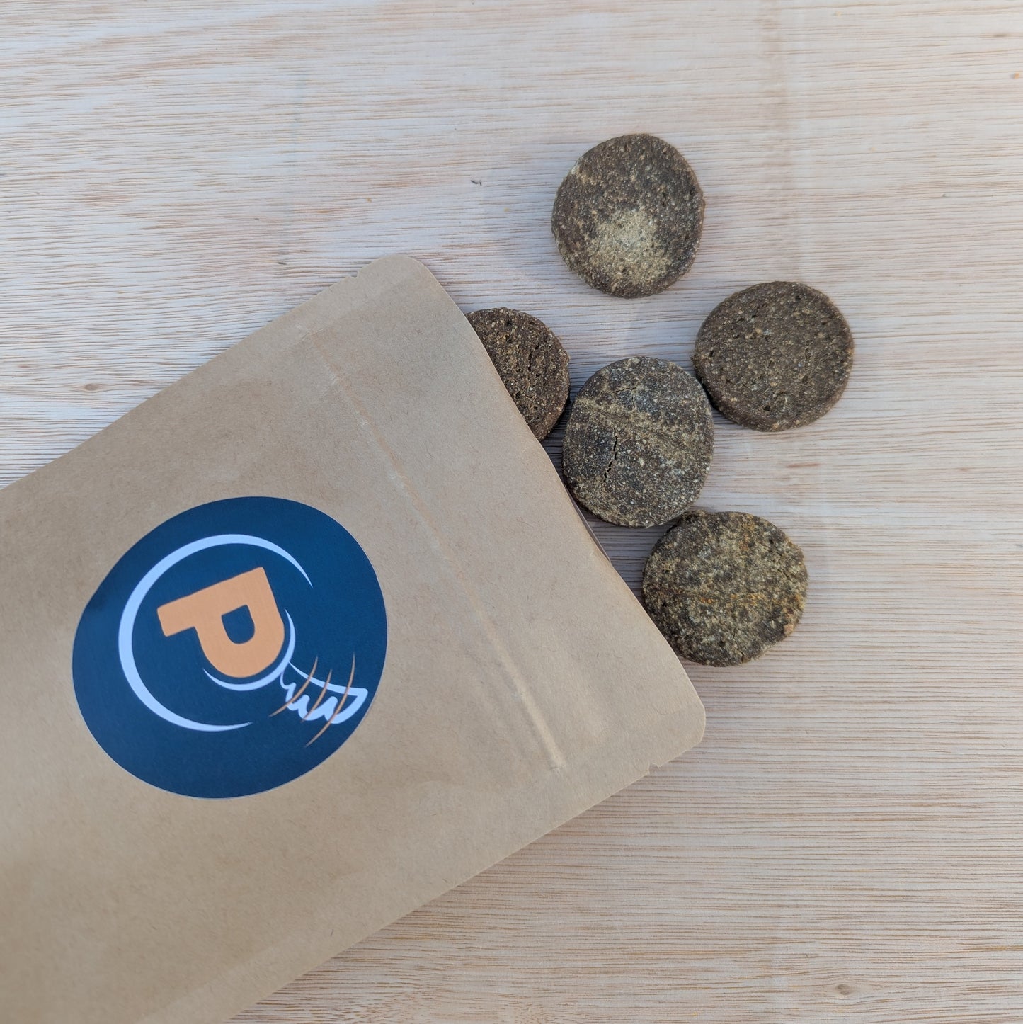 salmon cookies spilling out of a brown kraft resealable bag with a Proper Pet Stuff blue logo sticker on