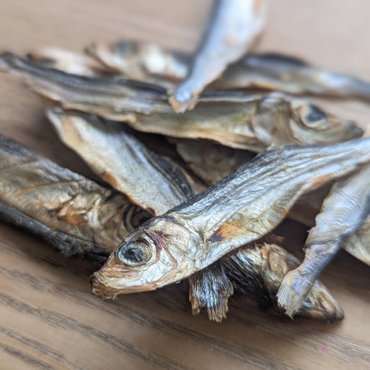 a close up of a sprat in the pile. The head and eye is closer to the camera. The others in the pile are blurred