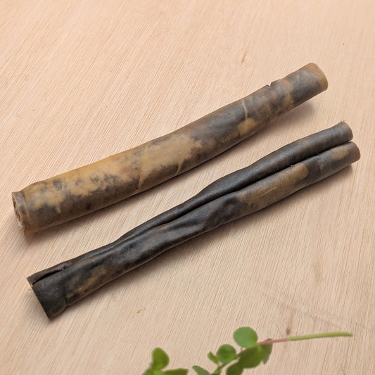 Two cylindrical camel skin rolls on a light wooden surface.