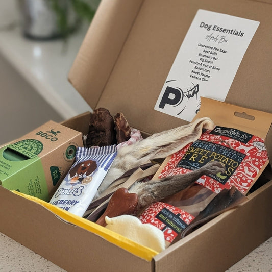 An open box containing dog treats chews and poo bags
