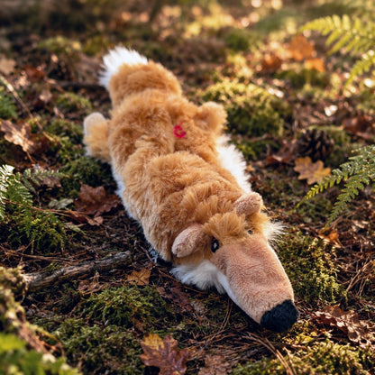 an orange fox plush toy on a woodland floor