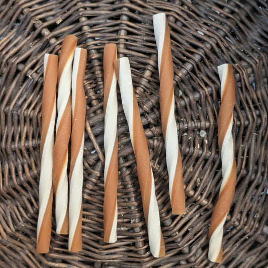 Twisted yellow and white chew sticks on a wicker surface