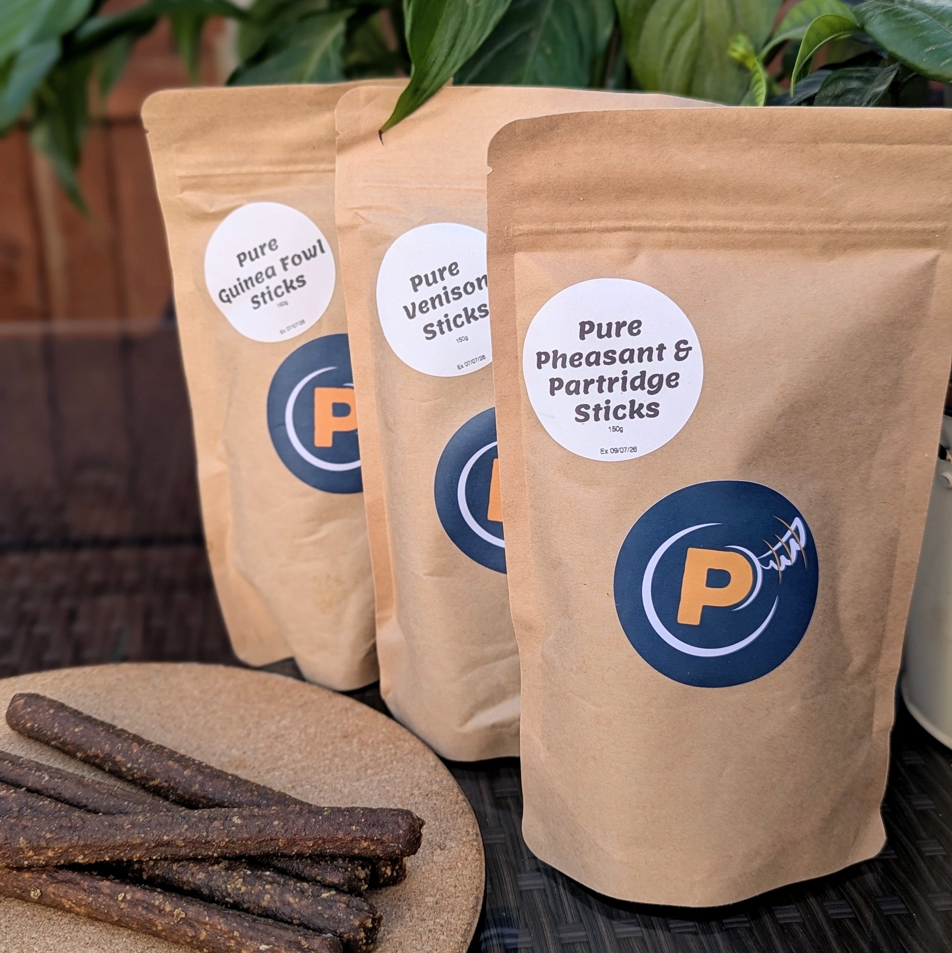 Three packages of Pure Guinea Fowl Sticks, Pure Venison Sticks, and Pure Pheasant & Partridge Sticks with a visible brand logo.