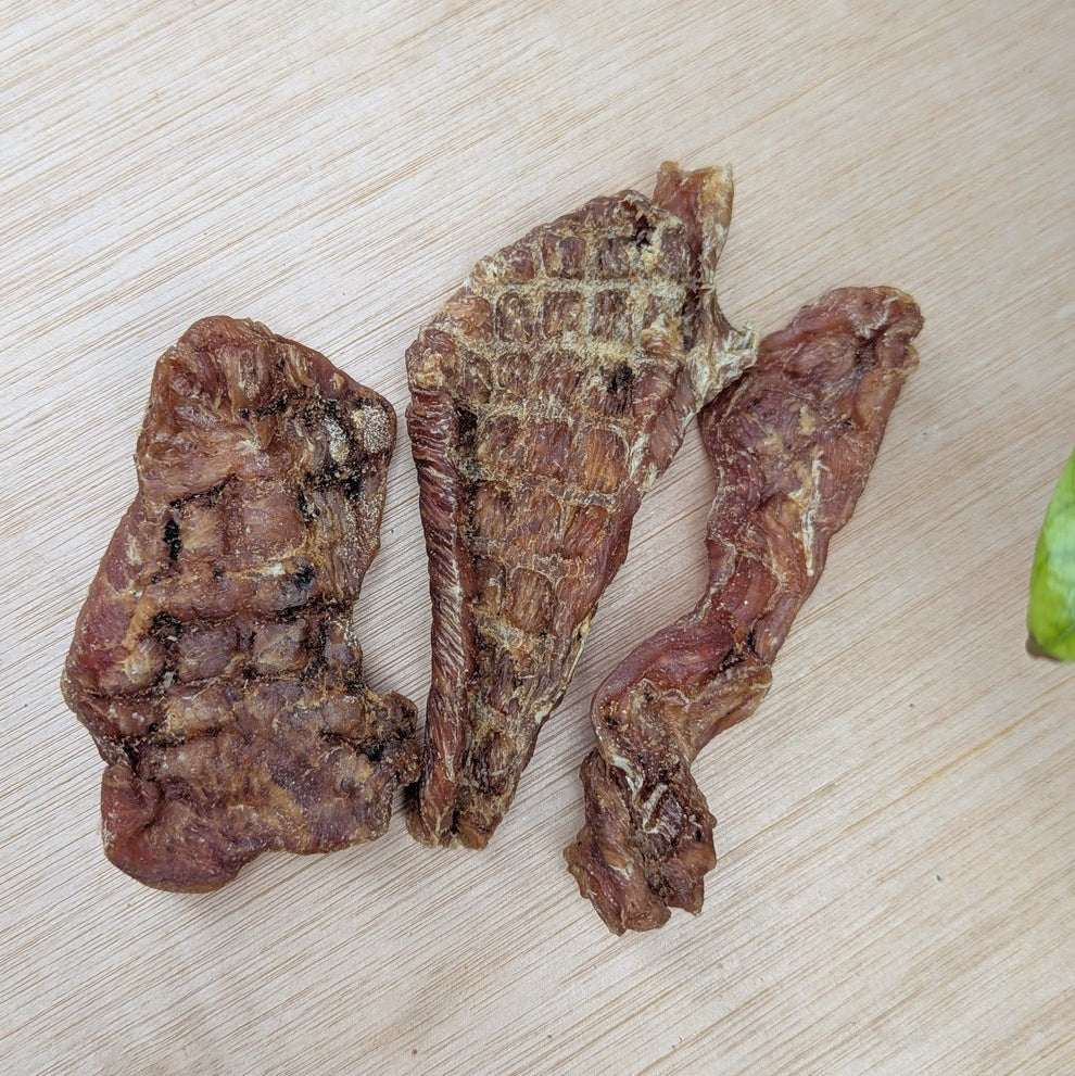 Three pieces of dried turkey filleton a wooden surface