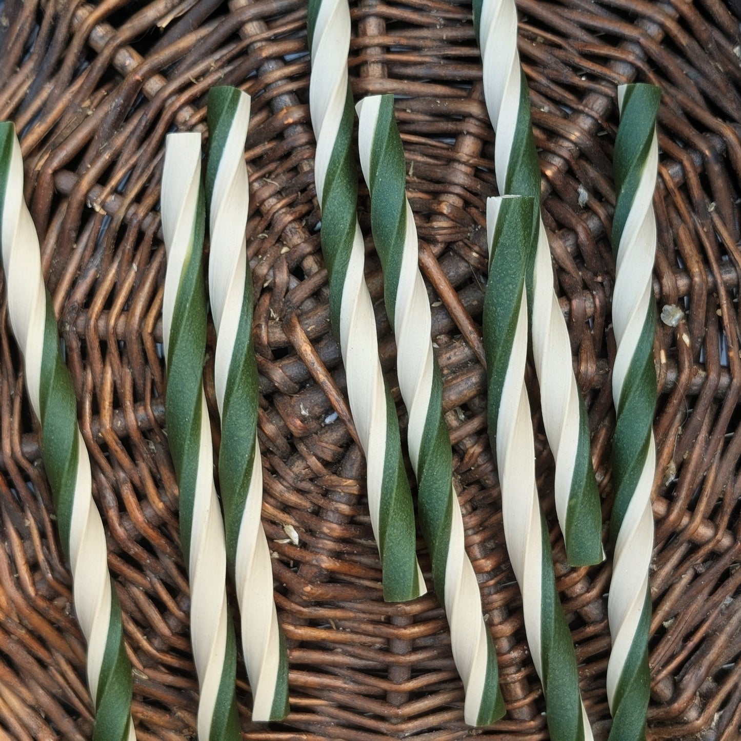 Green and white striped chew sticks on a wicker surface