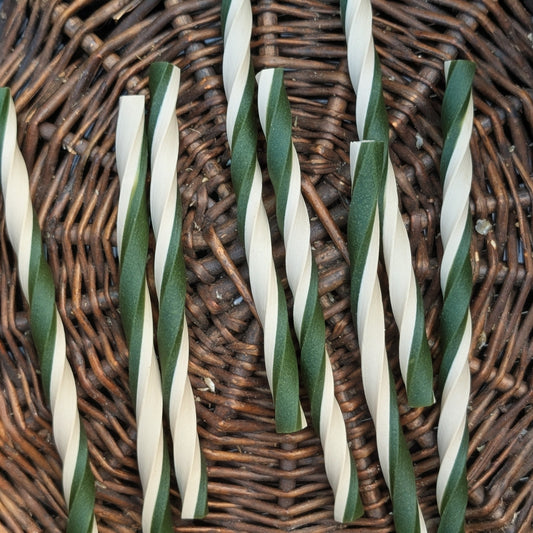 Green and white striped chew sticks on a wicker surface
