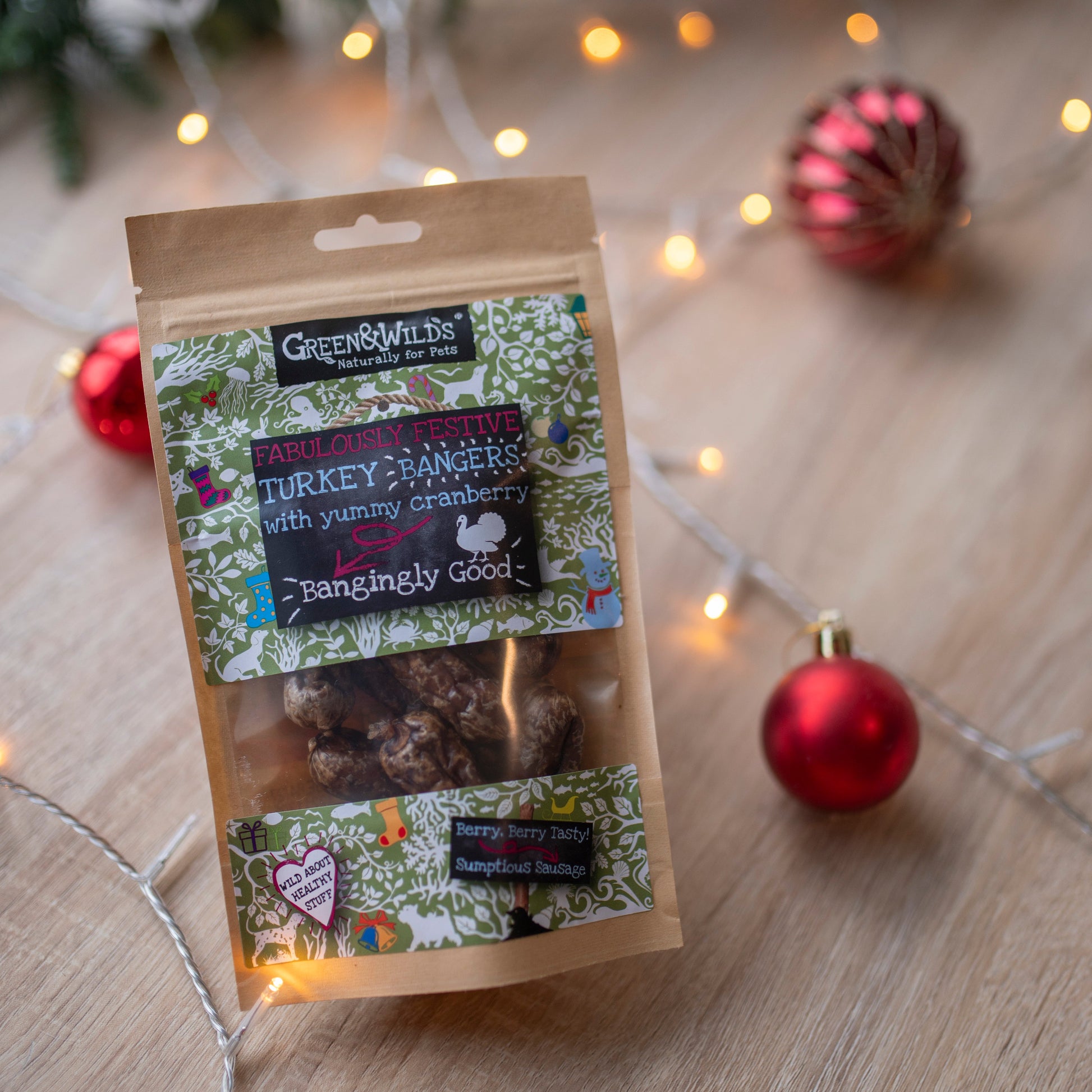 Package of Green & wilds christmas turkey bangers on a wooden surface with Christmas decorations surrounding