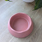The coral pink eco dog bowl is on a wooden table