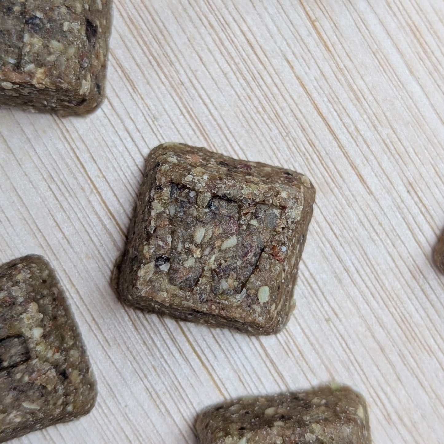Square-shaped letter denzels treats on a light wooden surface
