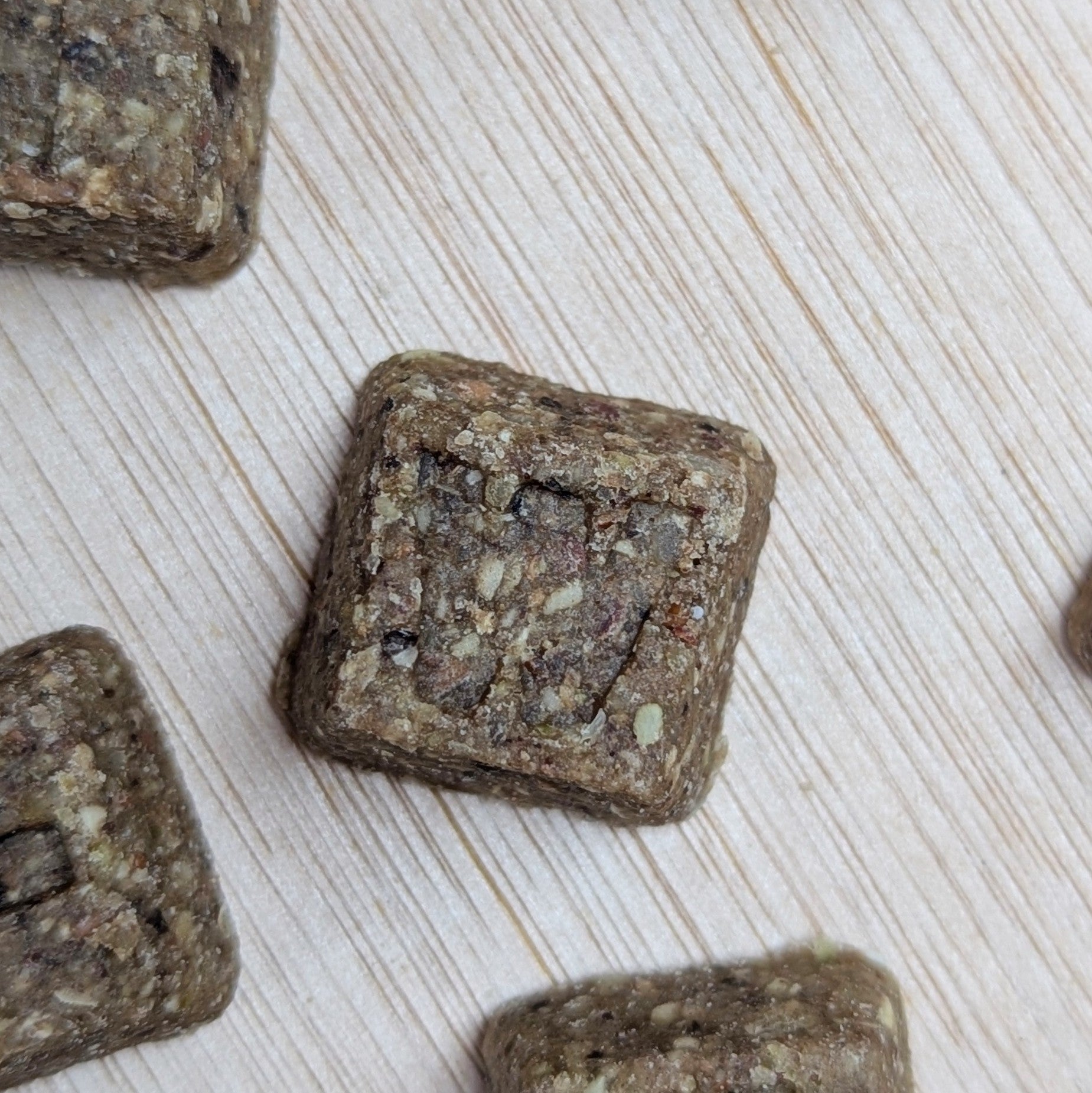 Square-shaped letter denzels treats on a light wooden surface