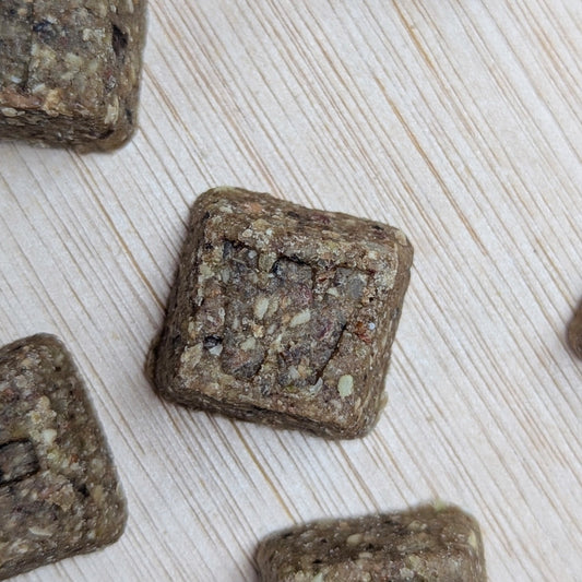 Square-shaped letter denzels treats on a light wooden surface