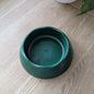 The forest green eco dog bowl is on a wooden table