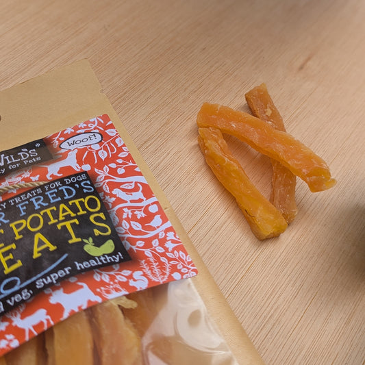 a close up of three sweet potato strips next to the bag on a wood surface
