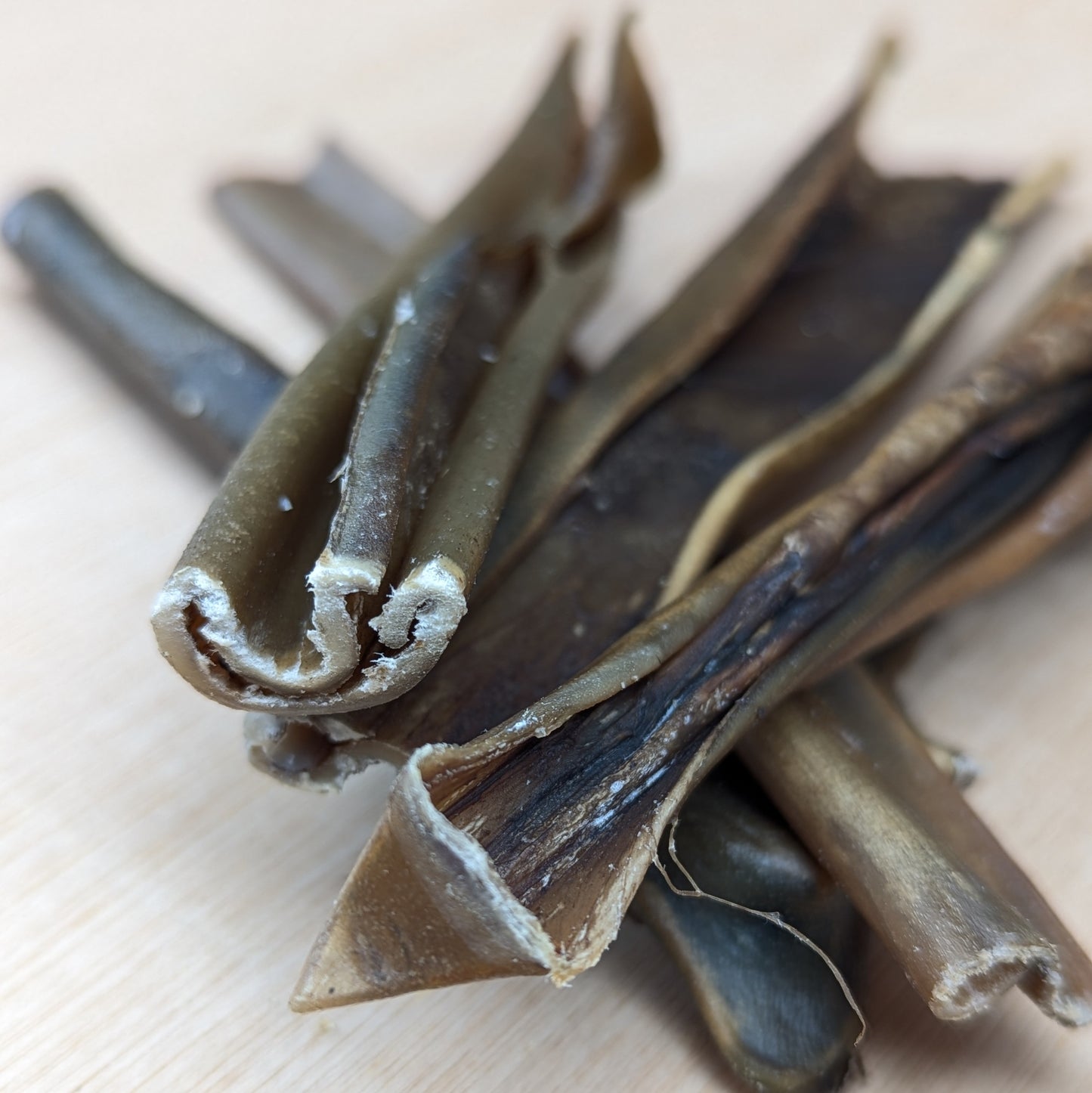Close-up of dried venison skin, they are dark and on a light wooden surfaceed 