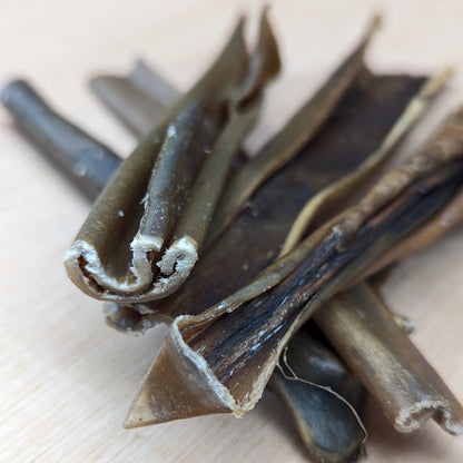 Close-up of dried venison skin, they are dark and on a light wooden surfaceed 